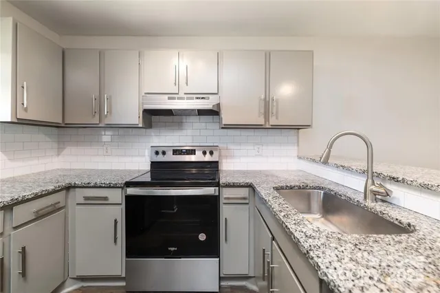 a kitchen with a sink stove top oven and cabinets