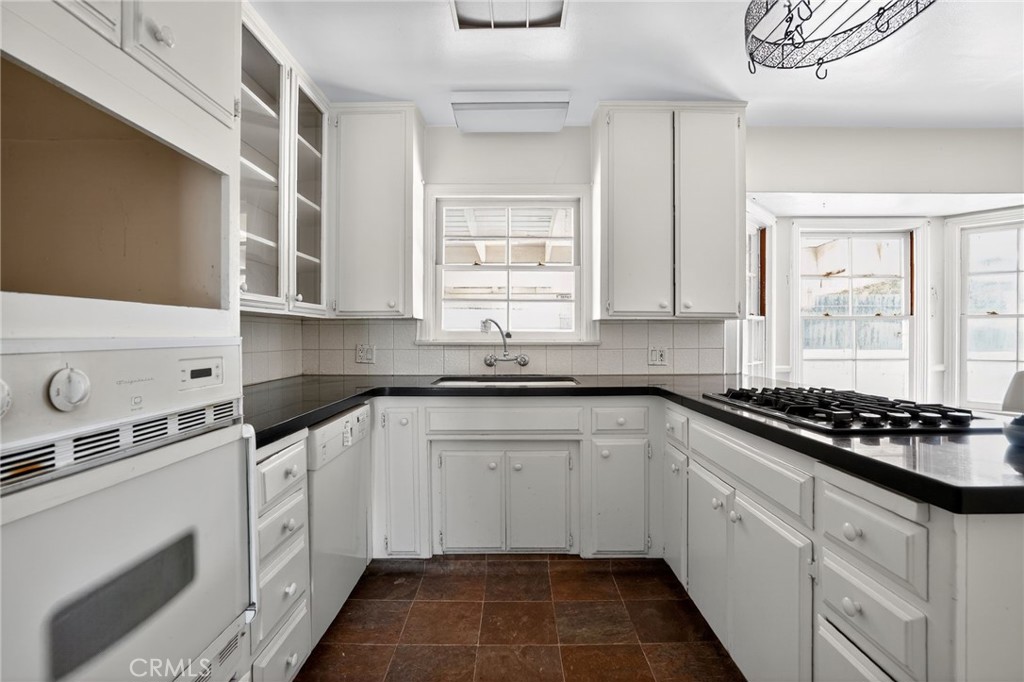 1717 Locust Ravine Bakersfield, CA 93306 - Photo 8 of 29 a white kitchen with granite countertop a stove a sink and dishwasher a cabinets with wooden floor