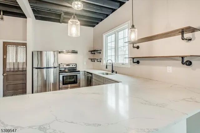 a kitchen with stainless steel appliances kitchen island granite countertop a refrigerator and a sink