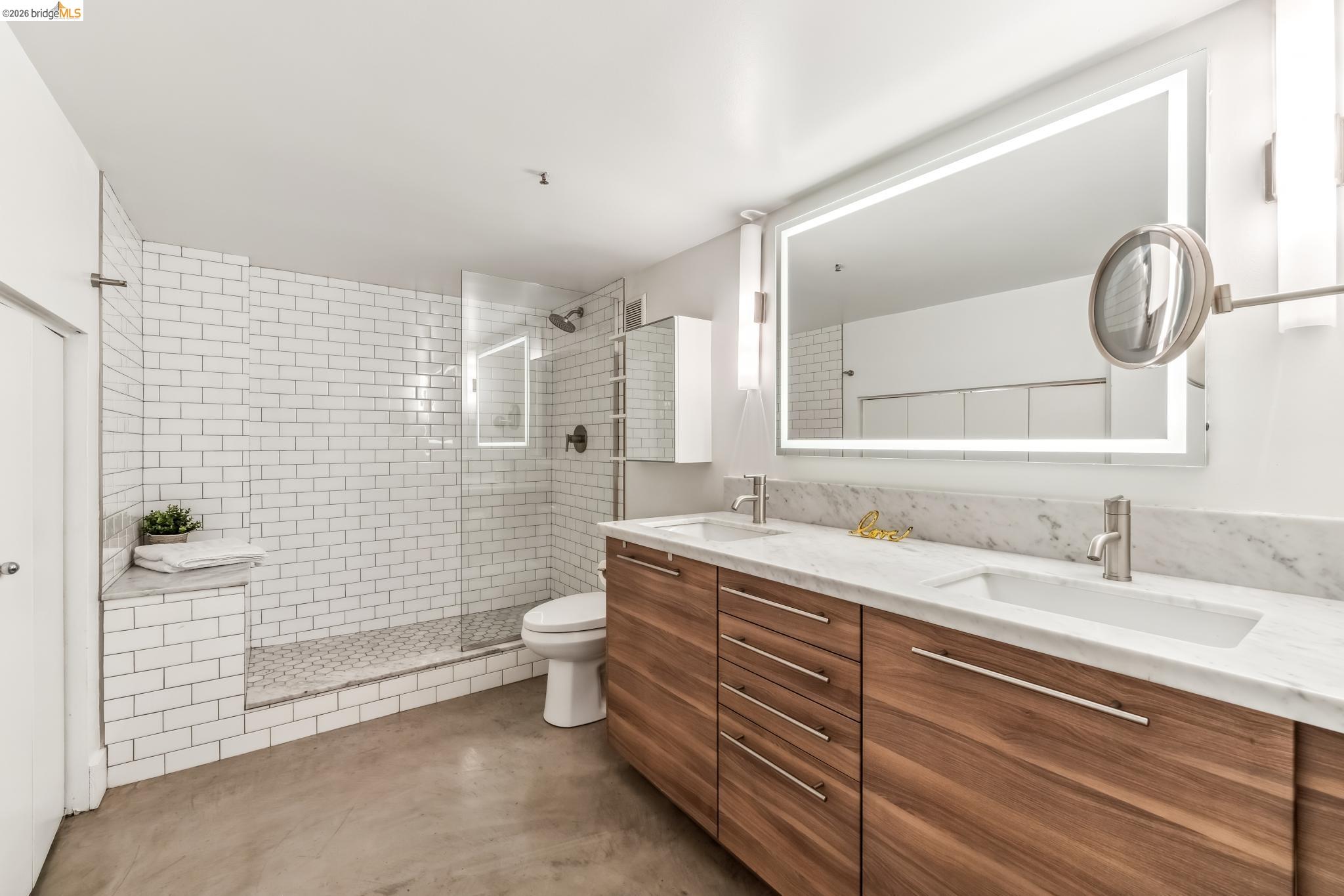 255 3rd Street, Unit 206 Oakland, CA 94607 - Photo 6 of 7 Double vanity featuring wood-finish cabinetry, integrated sinks, and a marble countertop