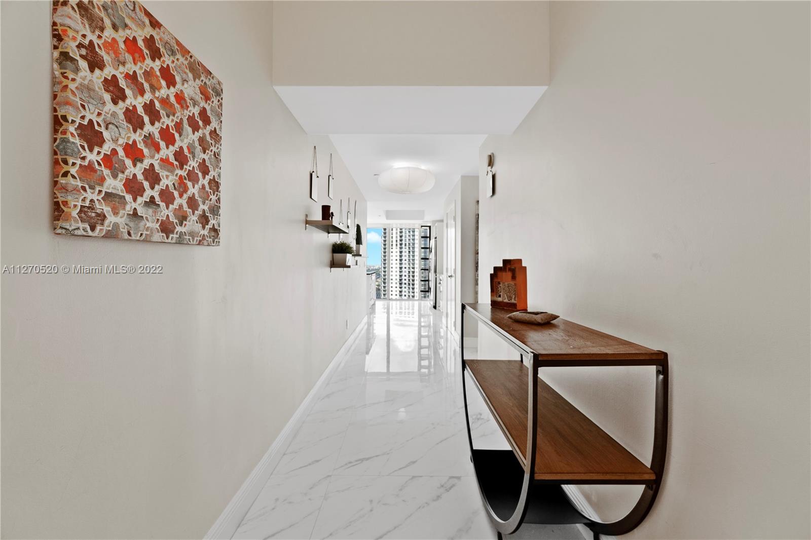 888 Biscayne Boulevard, Unit 3301 Miami, FL 33132 - Photo 11 of 29 a hallway with a flower pot and a bookshelf