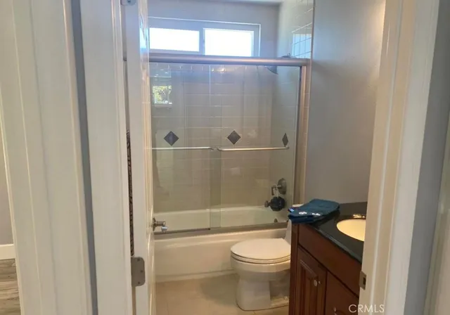 a bathroom with a granite countertop bathtub shower sink mirror and toilet