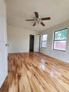 a view of empty room with wooden floor and fan