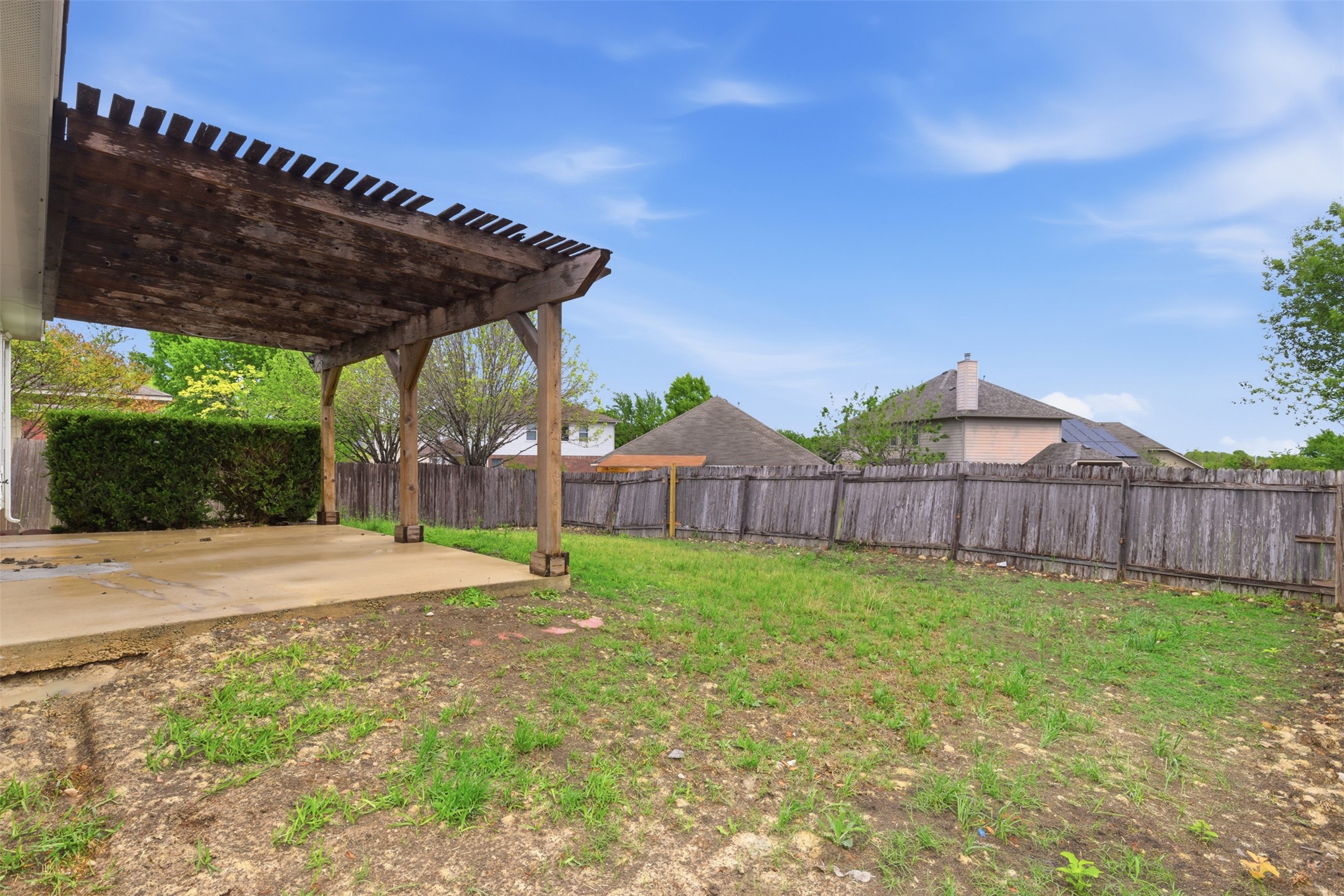 461 Hot Spring Valley Buda, TX 78610 - Photo 24 of 25 The property features a spacious backyard with a wooden fence and a pergola covering a concrete patio