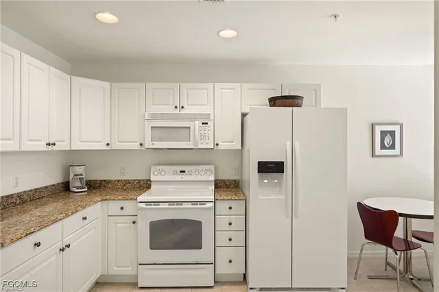 a kitchen with stainless steel appliances granite countertop a refrigerator sink stove and white cabinets