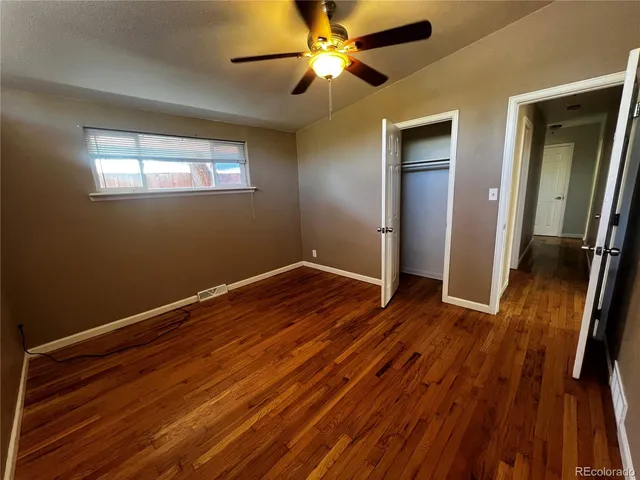 a view of empty room with wooden floor and fan
