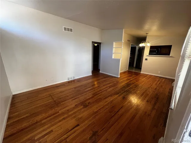 a view of empty room with wooden floor