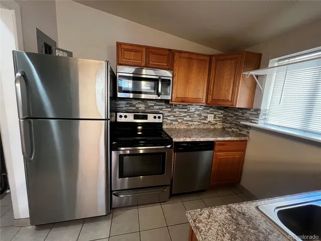 a kitchen with stainless steel appliances granite countertop a refrigerator stove and microwave