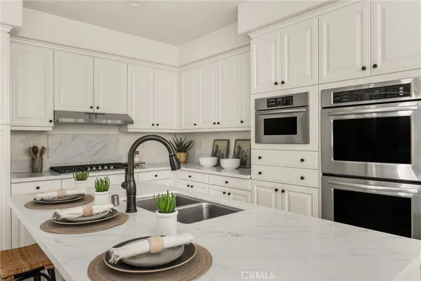 a kitchen with stainless steel appliances a refrigerator sink and white cabinets