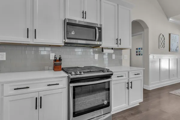 a kitchen with stainless steel appliances granite countertop white cabinets and stove