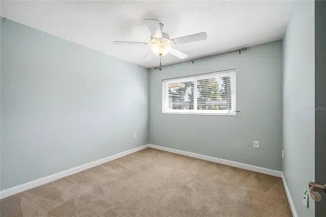 an empty room with a chandelier fan and windows