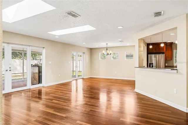 a view of empty room with wooden floor and kitchen view