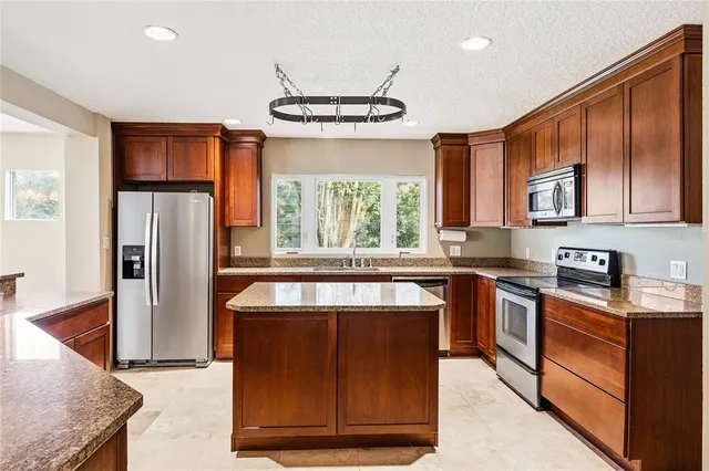 a kitchen with stainless steel appliances granite countertop a refrigerator a stove a sink and a microwave