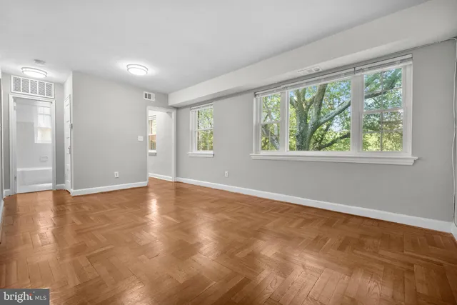 a view of an empty room with wooden floor and a window