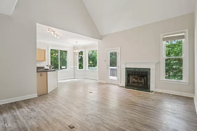 an empty room with windows a fireplace and wooden floor