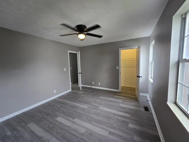 an empty room with wooden floor and windows