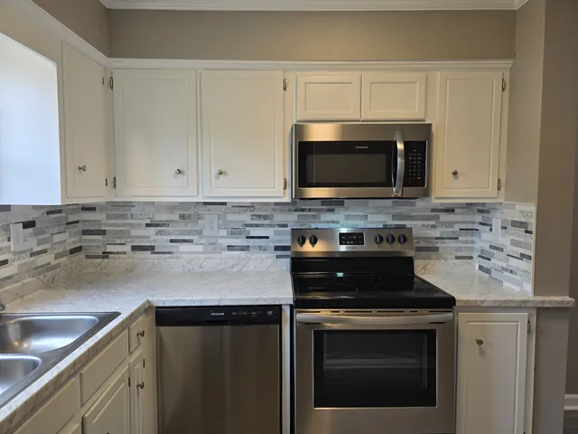 a kitchen with granite countertop white cabinets and black stainless steel appliances