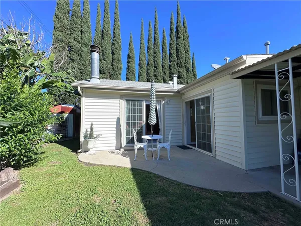 a view of a chair and table in backyard of the house