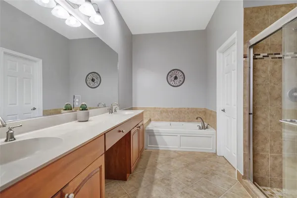 a bathroom with a tub sink double vanity and shower