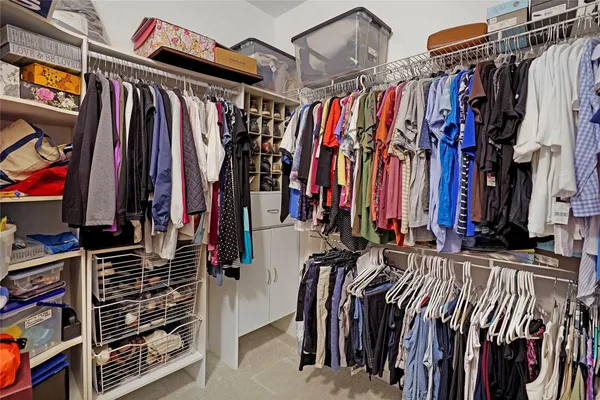 a view of walk in closet with clothes and shoes