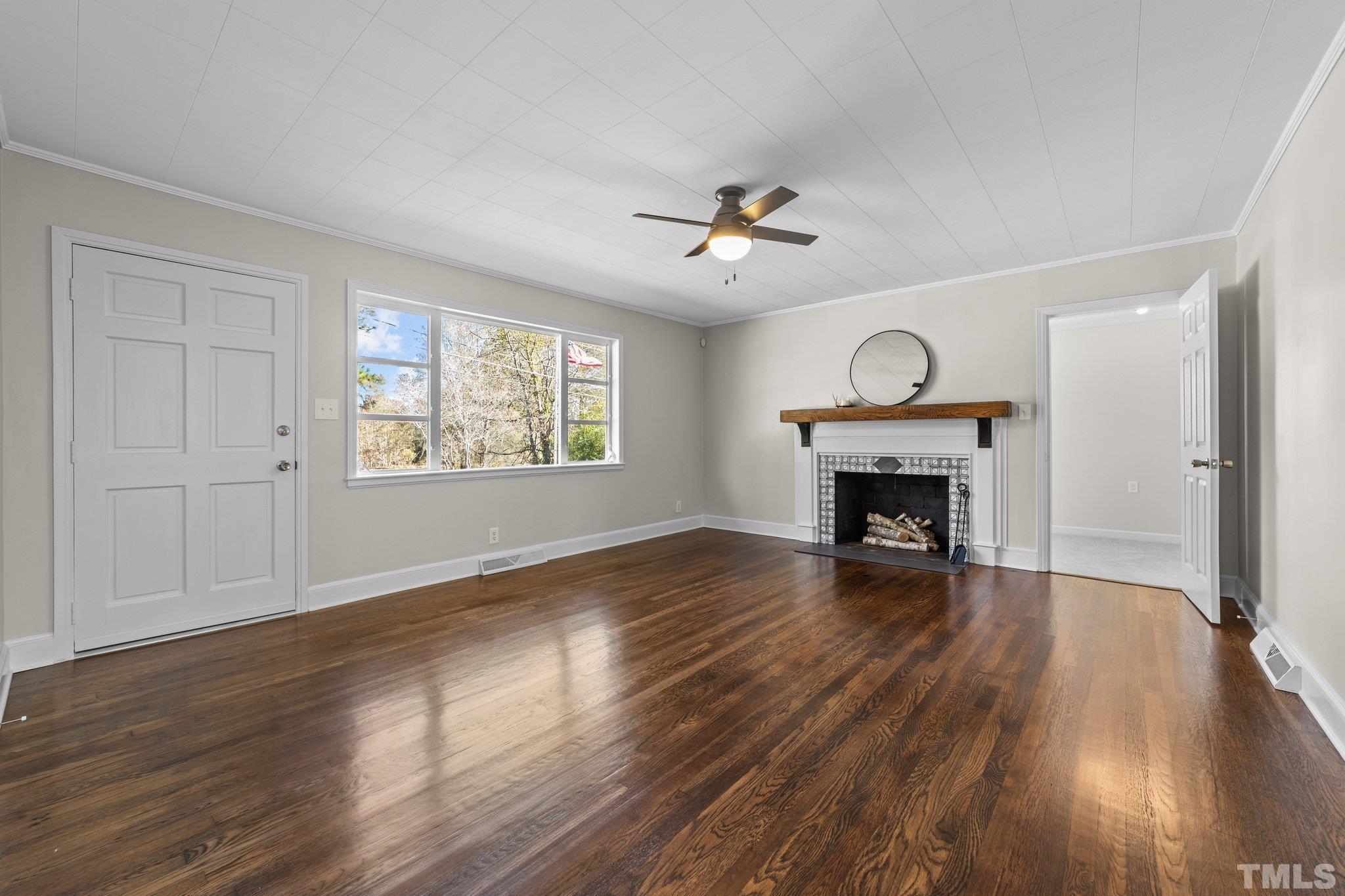 908 Goodwin Road Durham, NC 27712 - Photo 3 of 22 an empty room with wooden floor fireplace and windows