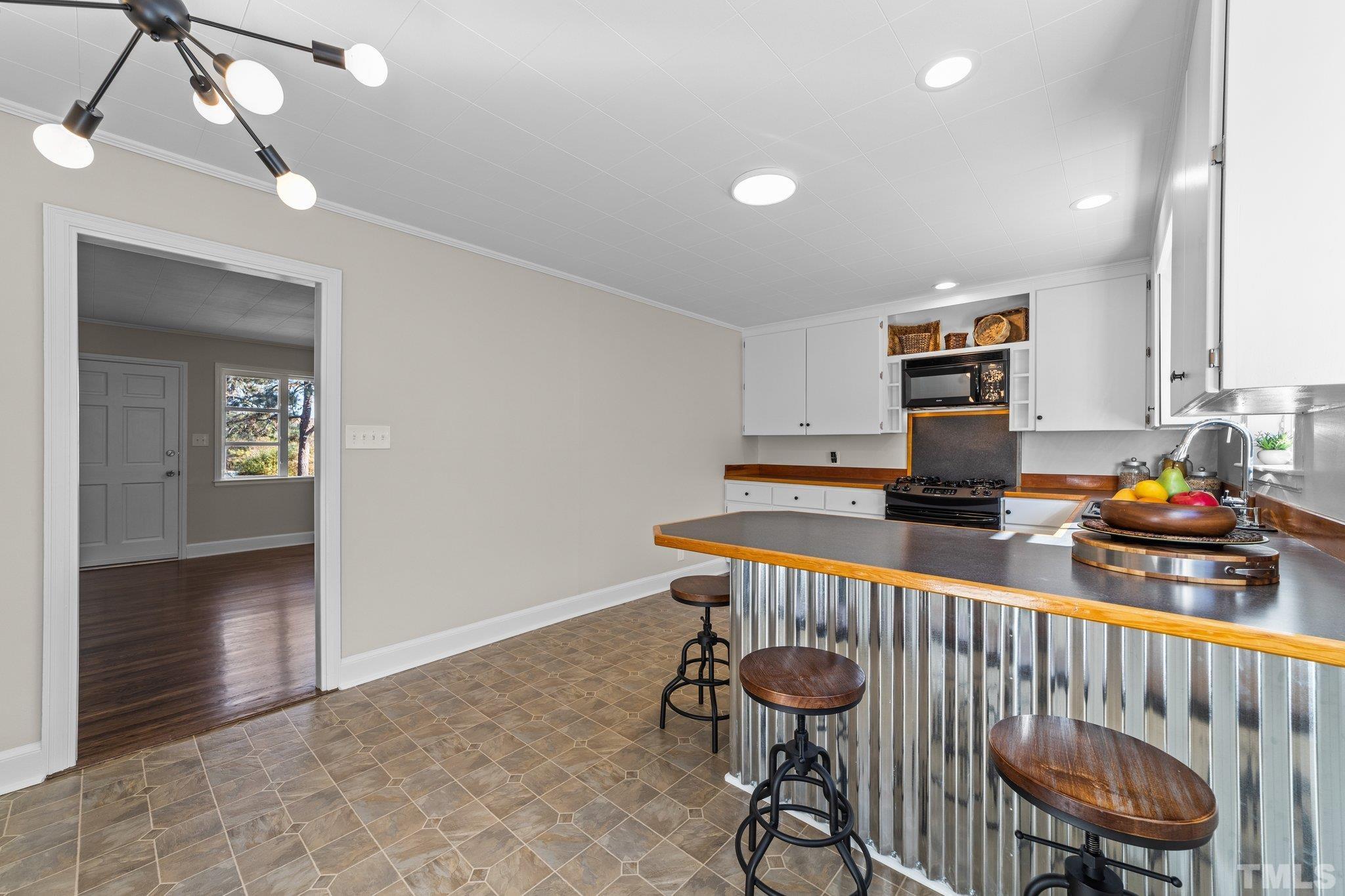 908 Goodwin Road Durham, NC 27712 - Photo 7 of 22 a kitchen with stainless steel appliances a stove a sink cabinets and a dining table