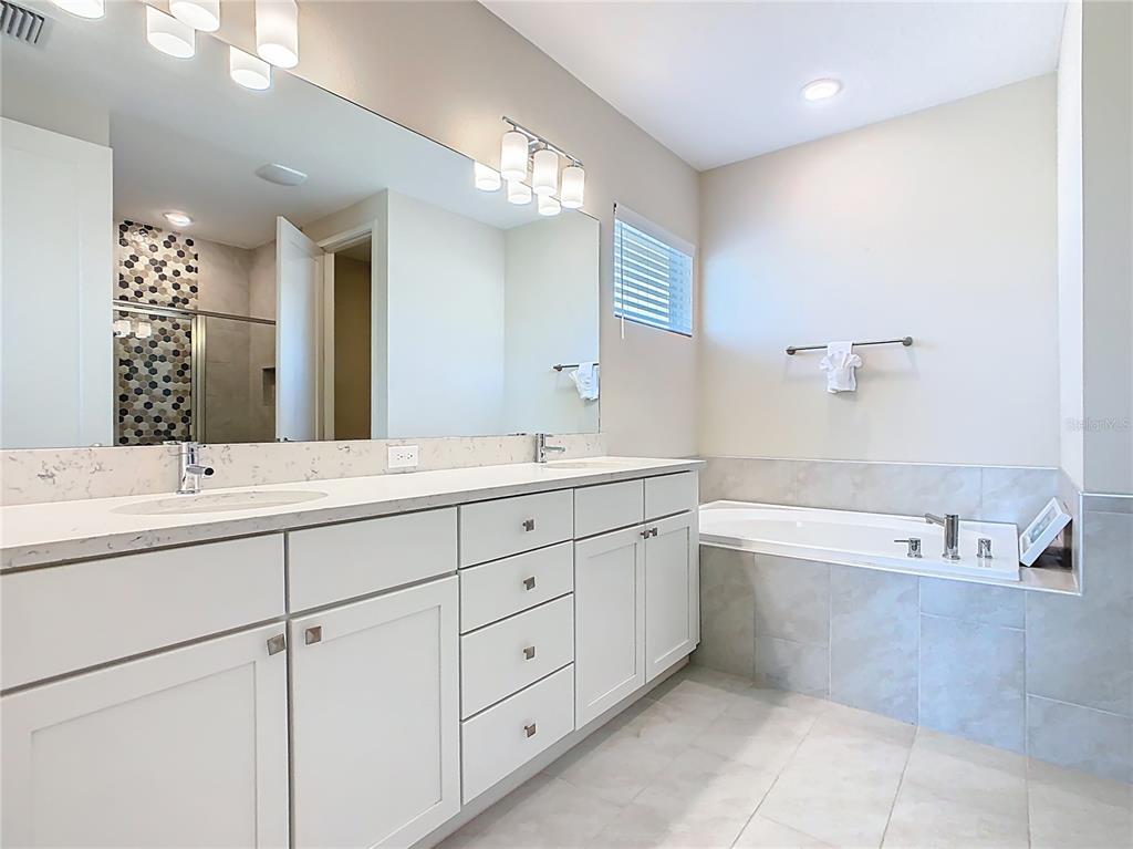 7948 Jacks Clb Drive Reunion, FL 34747 - Photo 60 of 85 a spacious bathroom with a double vanity sink mirror and bathtub