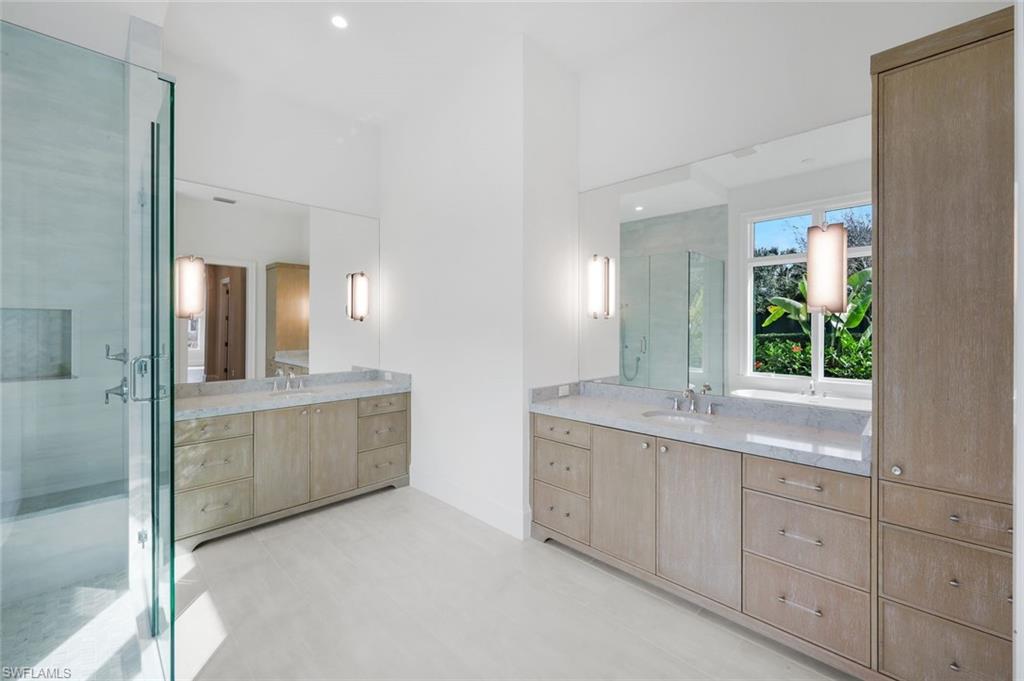 16728 Enclave Circle Naples, FL 34110 - Photo 21 of 49 Bathroom with two vanities, a stall shower, and recessed lighting