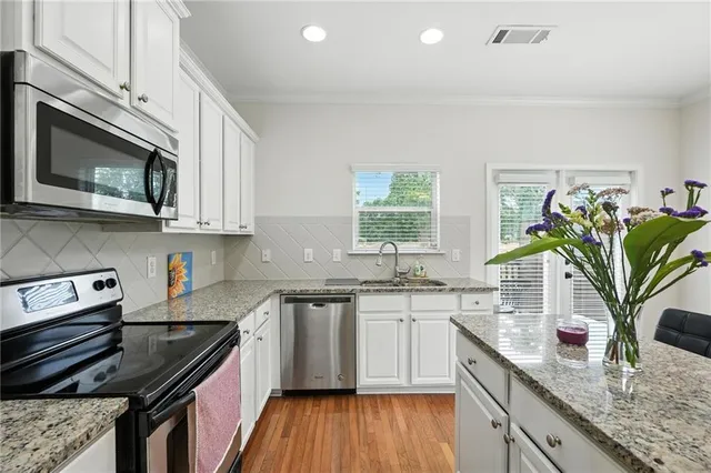 a kitchen with stainless steel appliances a sink dishwasher stove microwave and cabinets