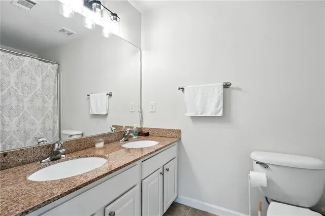 a bathroom with a granite countertop sink a toilet and mirror