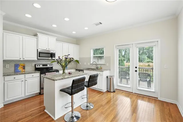 a kitchen with stainless steel appliances granite countertop a stove top oven a sink dishwasher and a refrigerator with wooden floor