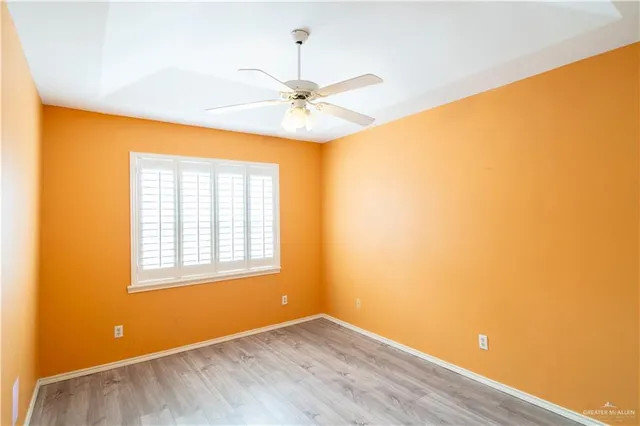 a view of an empty room with window and wooden floor