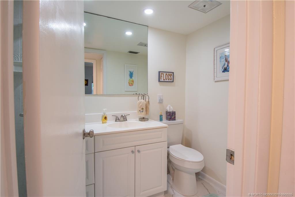1866 Southwest Palm City Road, Unit 101 Stuart, FL 34994 - Photo 13 of 23 a bathroom with a toilet sink vanity and mirror