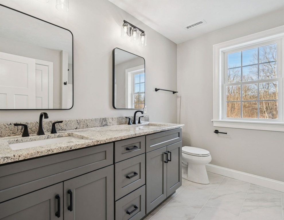 140 Ridge Road Rutland, MA 01543 - Photo 28 of 39 a bathroom with a granite countertop toilet a double vanity sink a mirror and a window