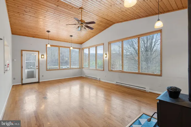 a view of an empty room with a window and wooden floor
