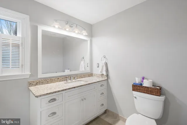 a bathroom with a granite countertop sink toilet and mirror
