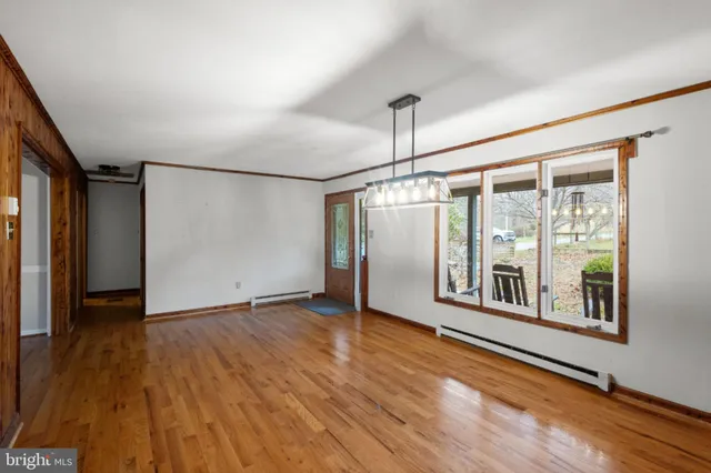 a view of an empty room with a window and wooden floor