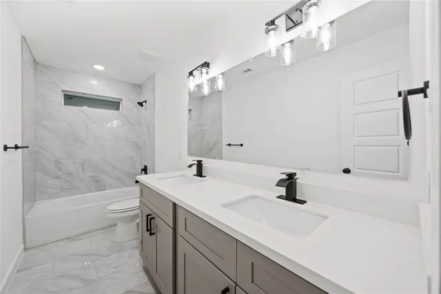 a bathroom with a sink a toilet a mirror and shower