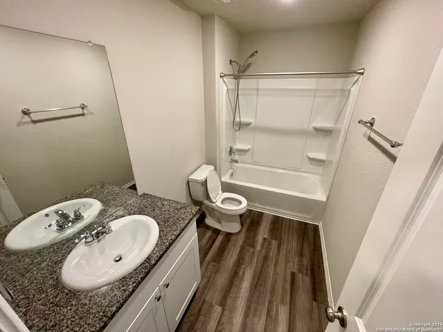 a bathroom with a granite countertop sink mirror vanity and toilet