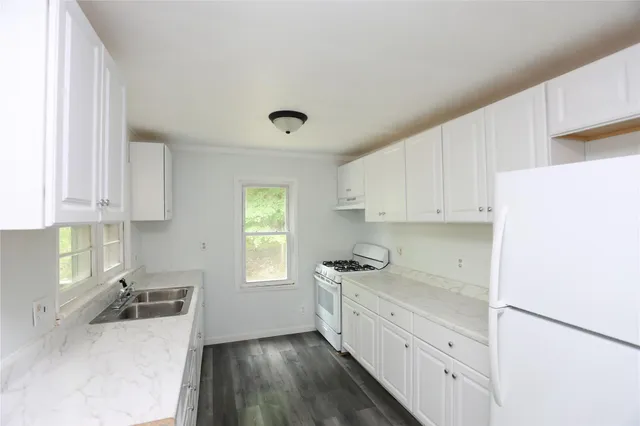 a kitchen with granite countertop white cabinets and white appliances
