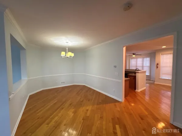 a view of a hallway with wooden floor and a kitchen