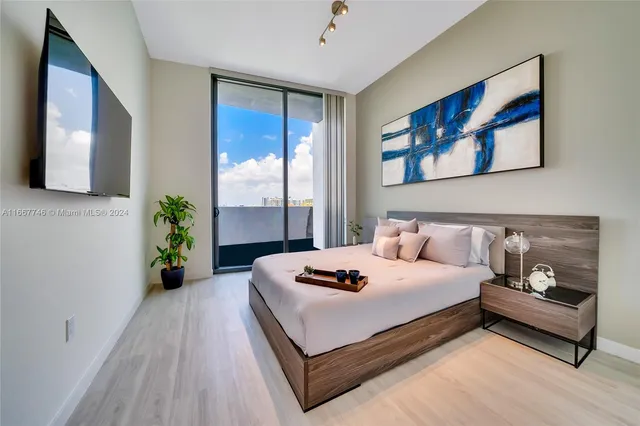 a bedroom with a bed and a flat tv screen on dresser