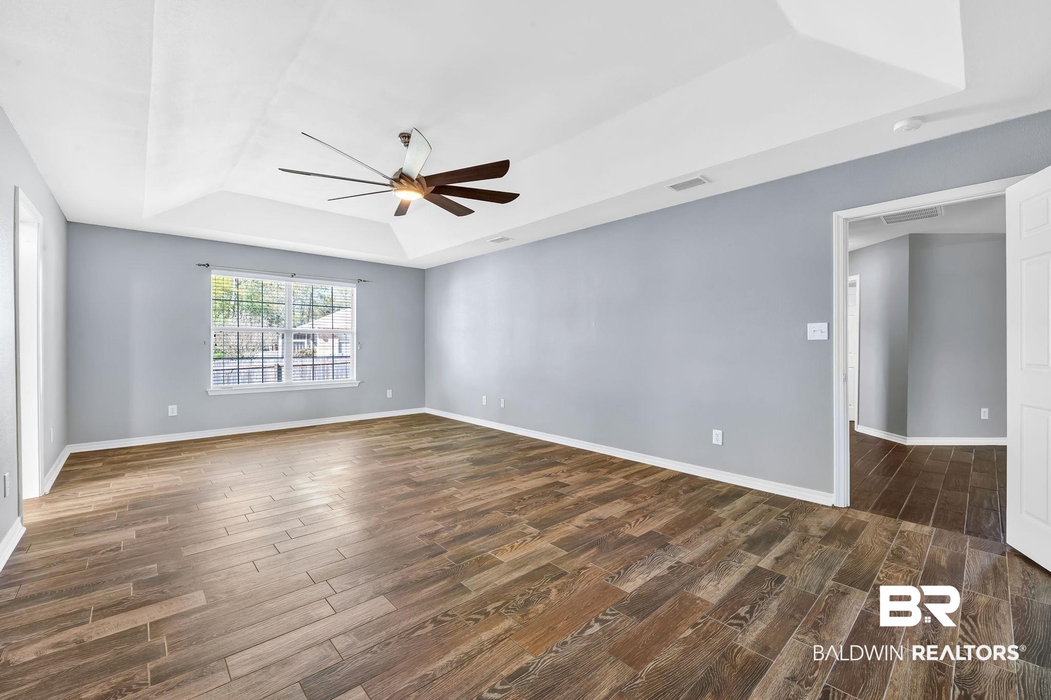 16444 Hamlet Lane Foley, AL 36535 - Photo 25 of 49 Empty room with a tray ceiling, dark wood-style floors, ceiling fan, and baseboards