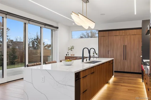 a large kitchen with kitchen island a large window a sink and stainless steel appliances