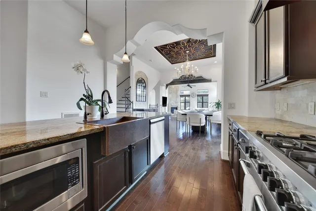 a kitchen with stainless steel appliances a sink dishwasher stove and oven with wooden floor