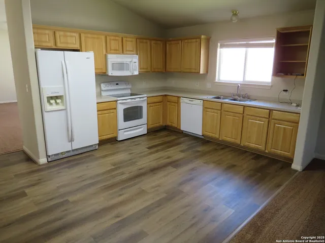 a kitchen with stainless steel appliances granite countertop a refrigerator a sink dishwasher a stove with wooden floors and cabinets