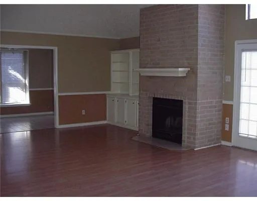 a view of empty room with wooden floor and fireplace