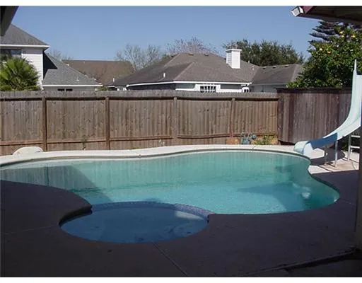 a view of a backyard with lawn chairs plants and wooden fence