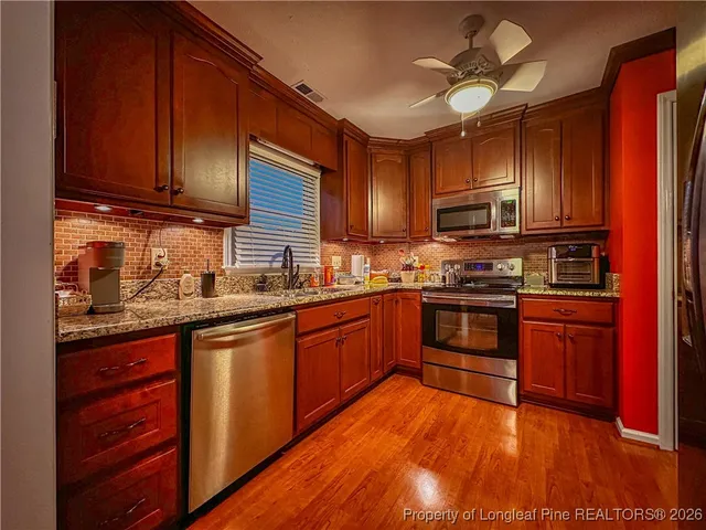 a kitchen with stainless steel appliances granite countertop wooden cabinets a stove top oven a sink and dishwasher