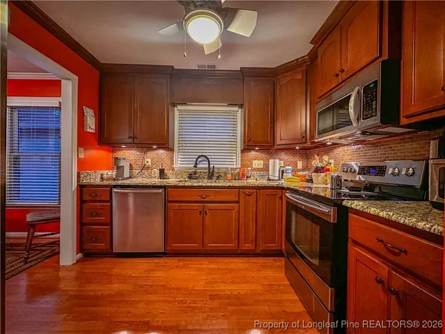 a kitchen with stainless steel appliances granite countertop wooden cabinets a stove top oven a sink and dishwasher